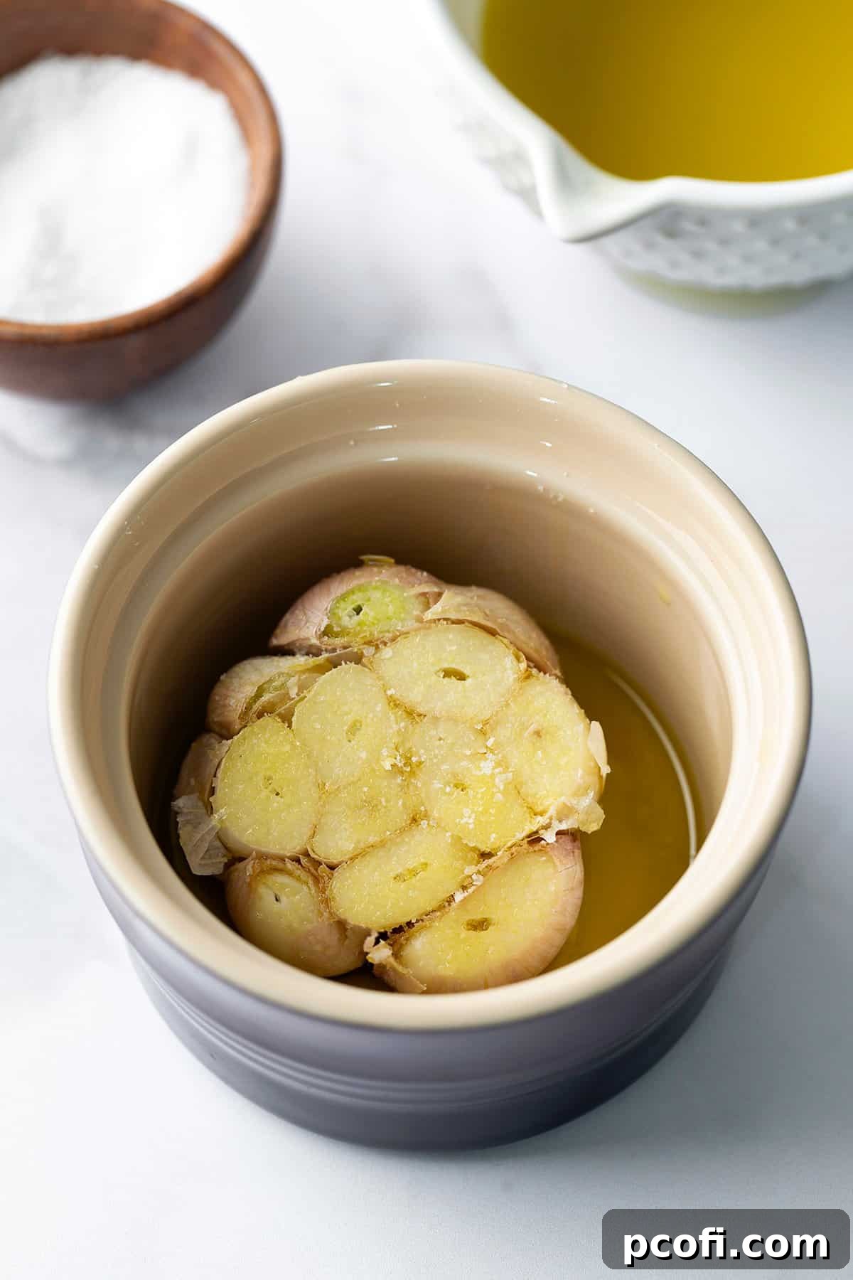 Garlic head placed in a small ramekin, drizzled with oil and salt.