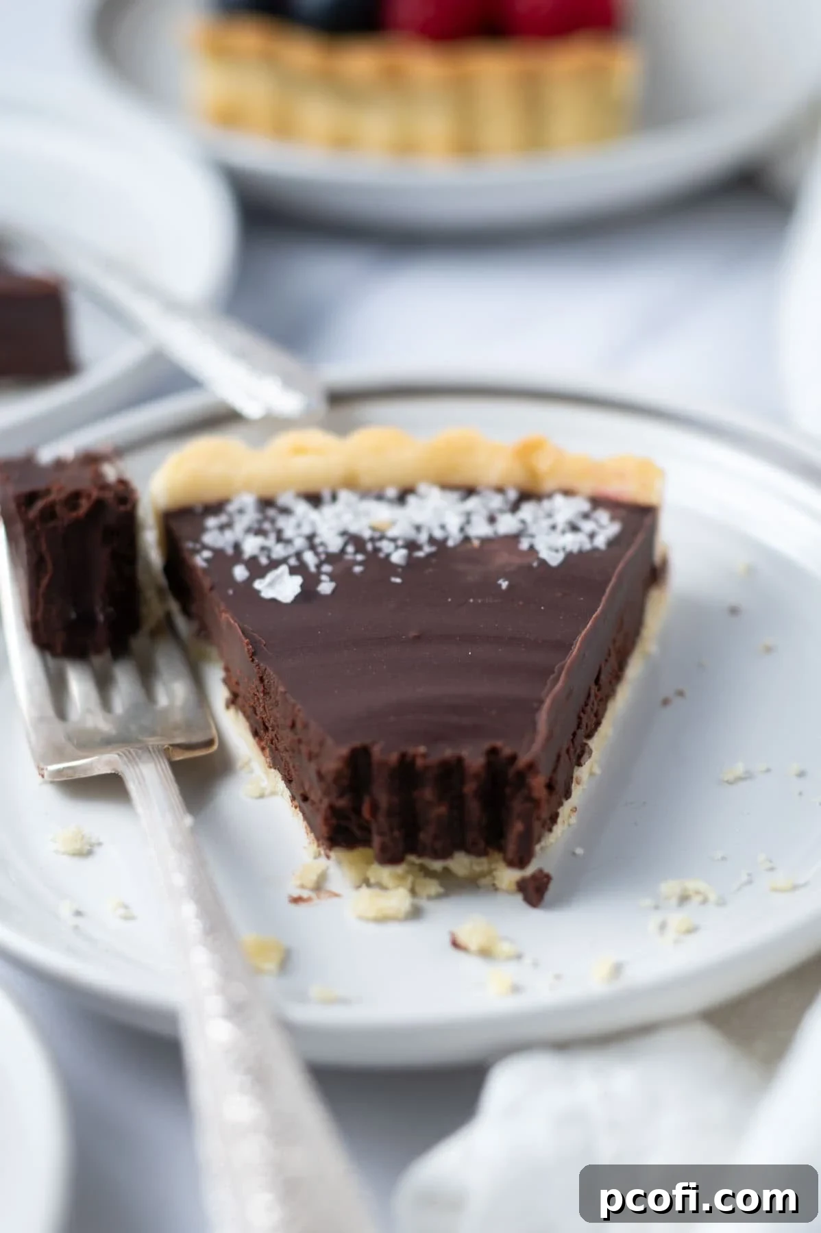a chocolate tart slice on a plate with a bite missing