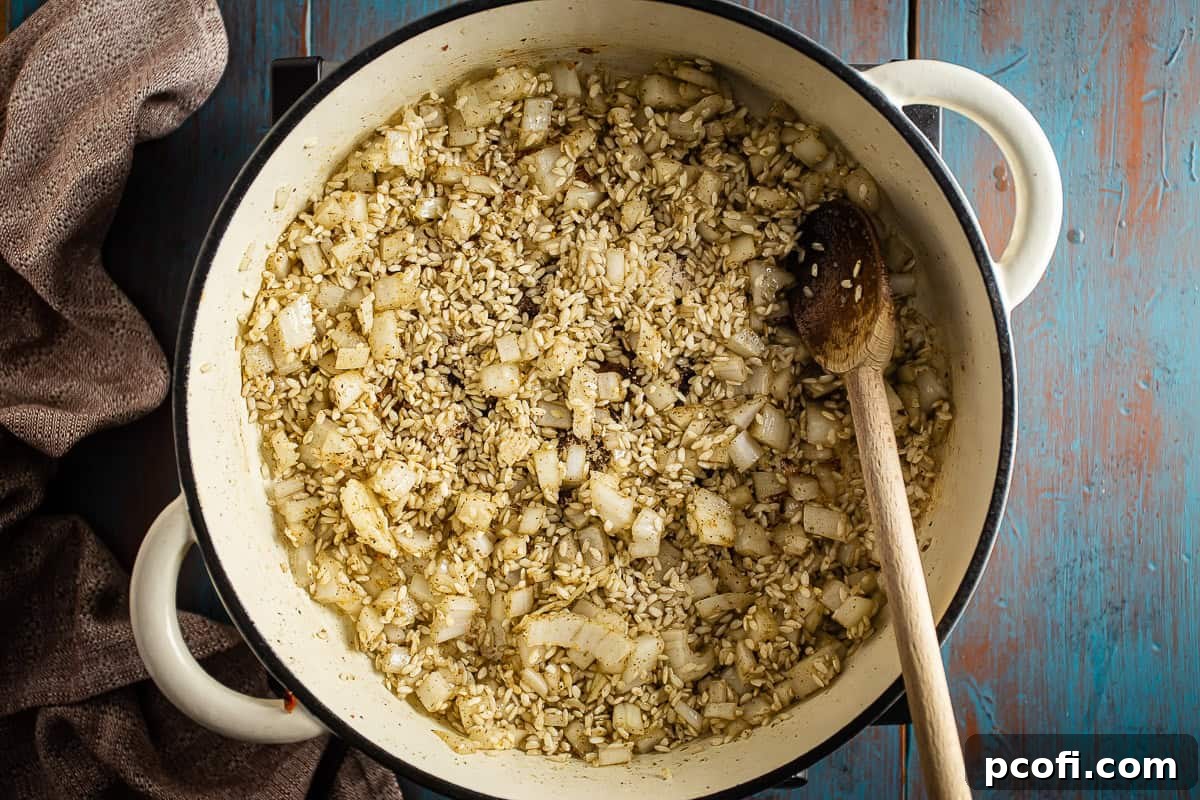 Onions and Arborio rice gently sautéing in a Dutch oven, becoming translucent and fragrant for pumpkin risotto.