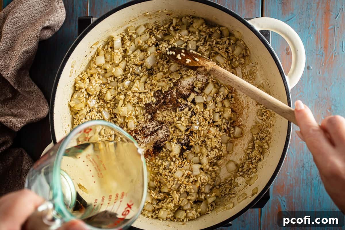 Dry white wine being added to the risotto base in a large Dutch oven, ready for deglazing and simmering.