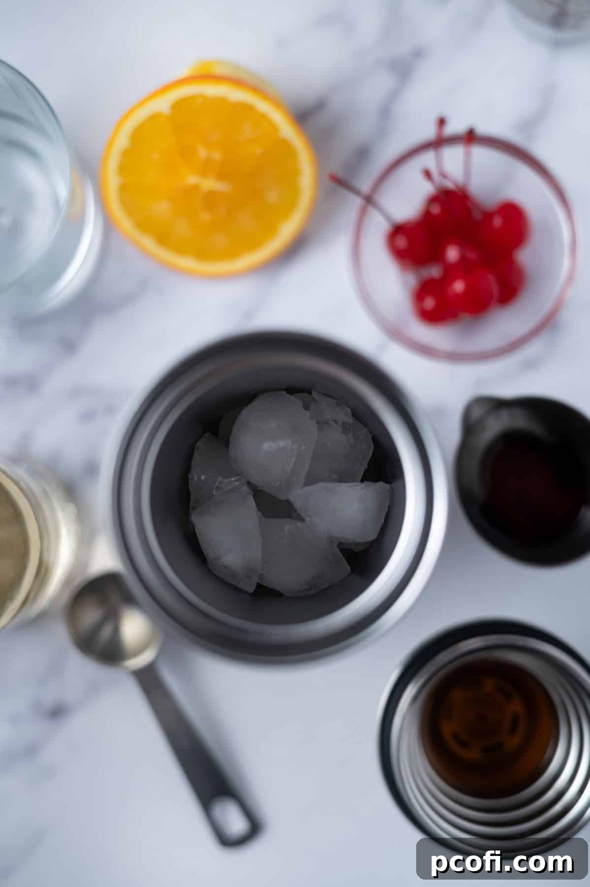Cocktail shaker filled with ice, surrounded by bottles of bourbon and amaretto, fresh orange slices, and cherries – ready for mixing an Amaretto Sour