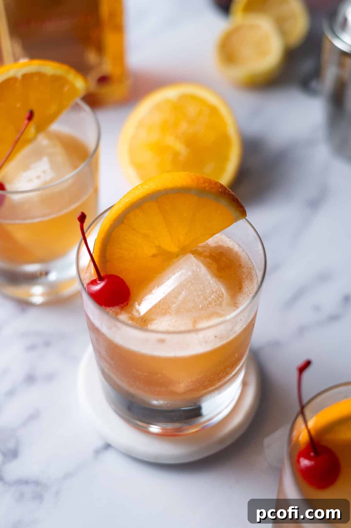 Downward view of a freshly made Amaretto Sour cocktail with lemon slices blurred in the background, showcasing the drink's vibrant color