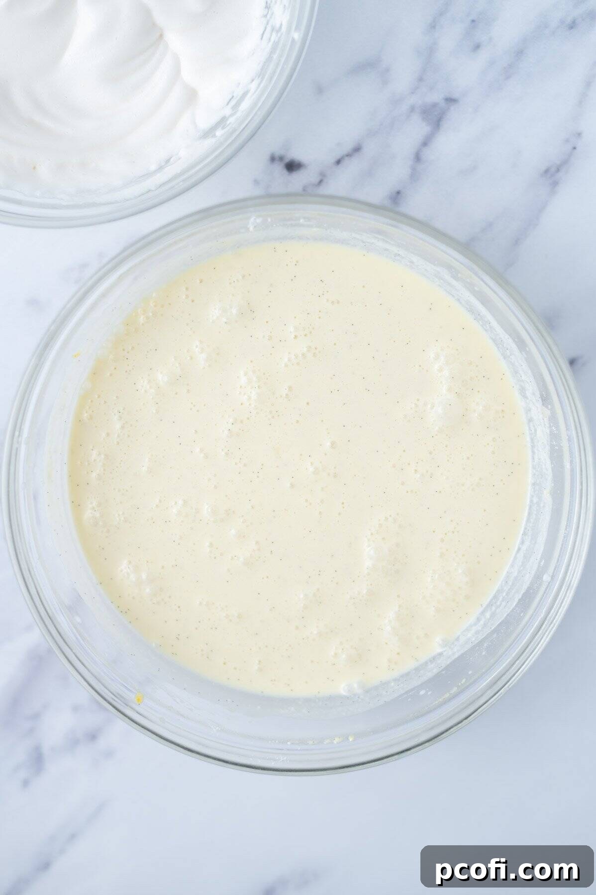 Magic custard cake batter in a glass bowl after all the milk has been added, now appearing quite thin