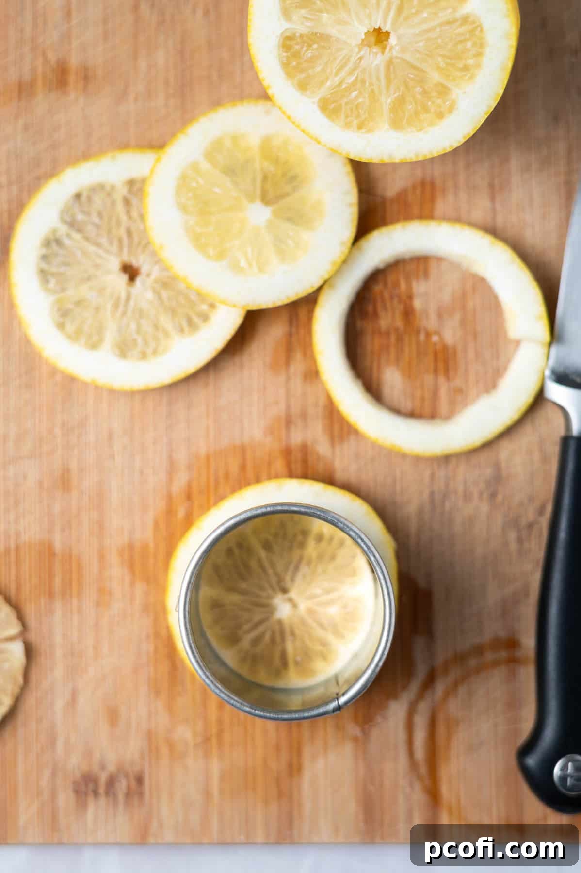 Lemon slices on a cutting board, with some fruit middles removed, ready for twisting into garnishes.