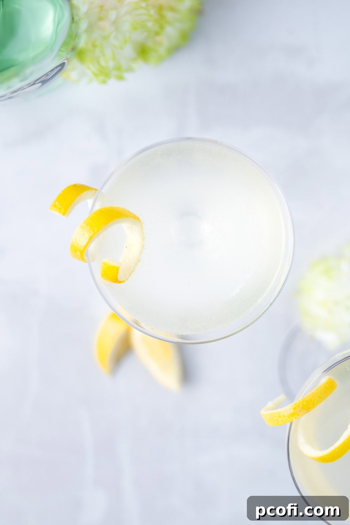 Overhead view of a perfectly mixed French 75 cocktail in a coupe glass, garnished with a lemon twist, ready to be enjoyed.