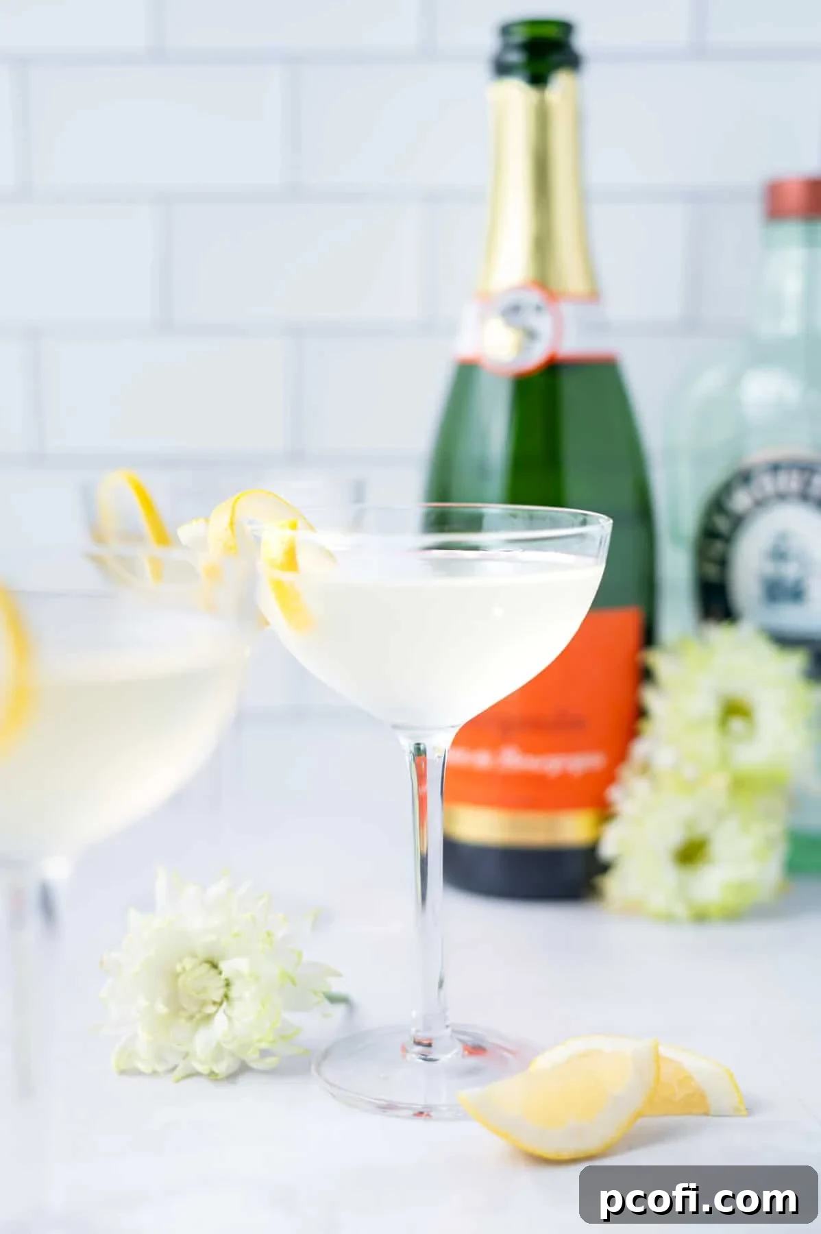 A festive arrangement of French 75 cocktails in elegant glasses, surrounded by fresh flowers, lemon slices, and bottles of gin and champagne, ready for a celebration.