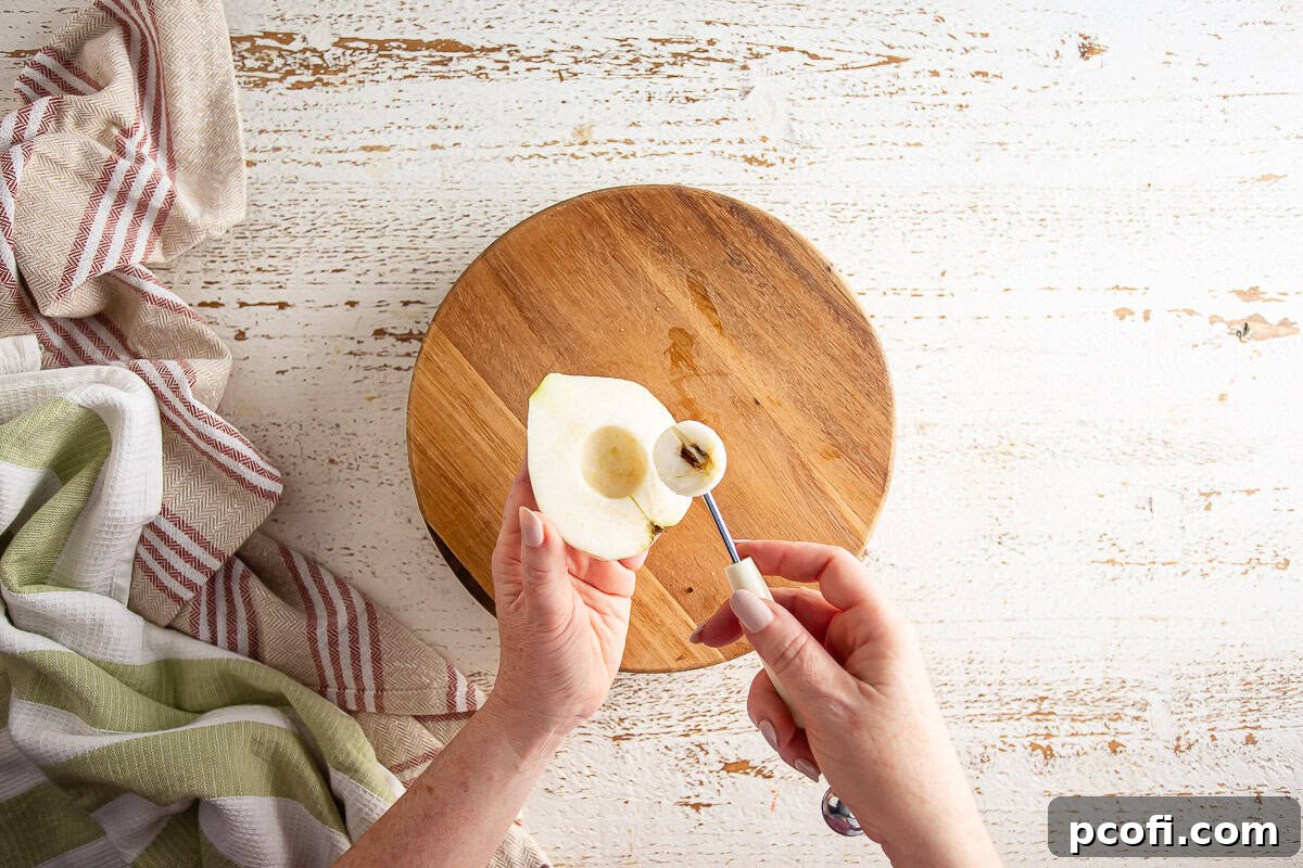 The process of removing the core from a pear using a melon baller for a pear tart.