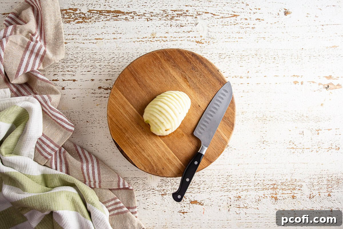 A cored pear expertly sliced into thin, uniform pieces, ready for arrangement in the tart.