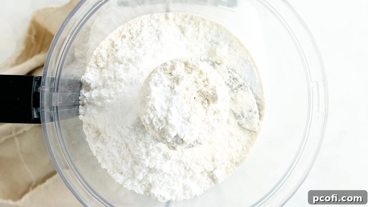 Dry ingredients for the tart crust, including flour, powdered sugar, and salt, in a food processor bowl.