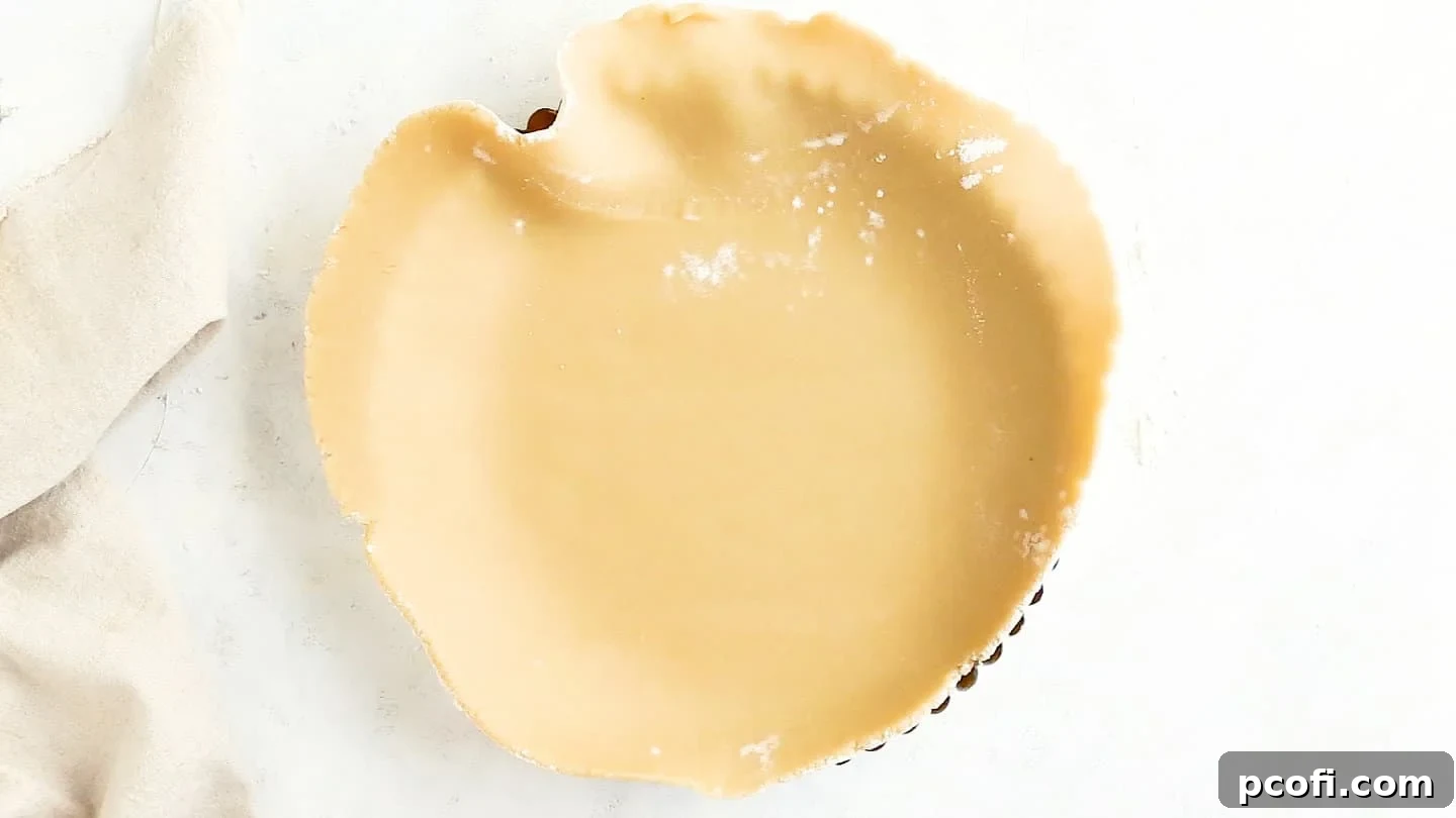 Tart dough carefully pressed into a fluted tart pan with a removable bottom.