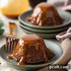 Individual sticky toffee pudding cakes on green plates, drizzled with toffee sauce.