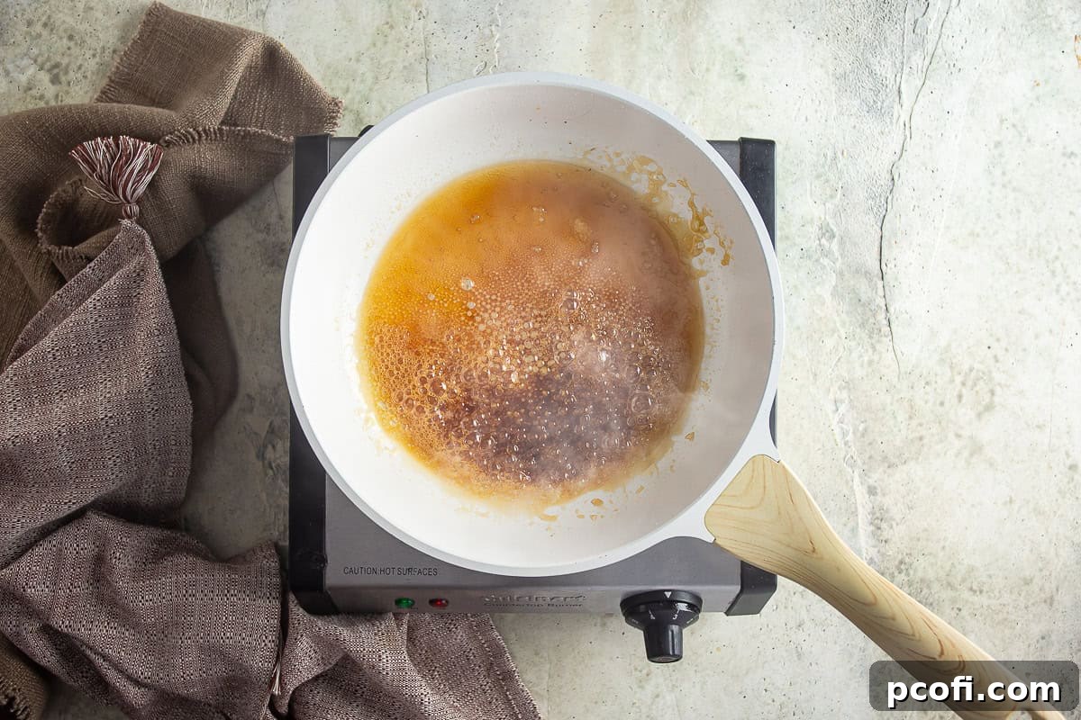 Granulated sugar and water caramelizing in a saucepan, turning into a deep amber liquid.