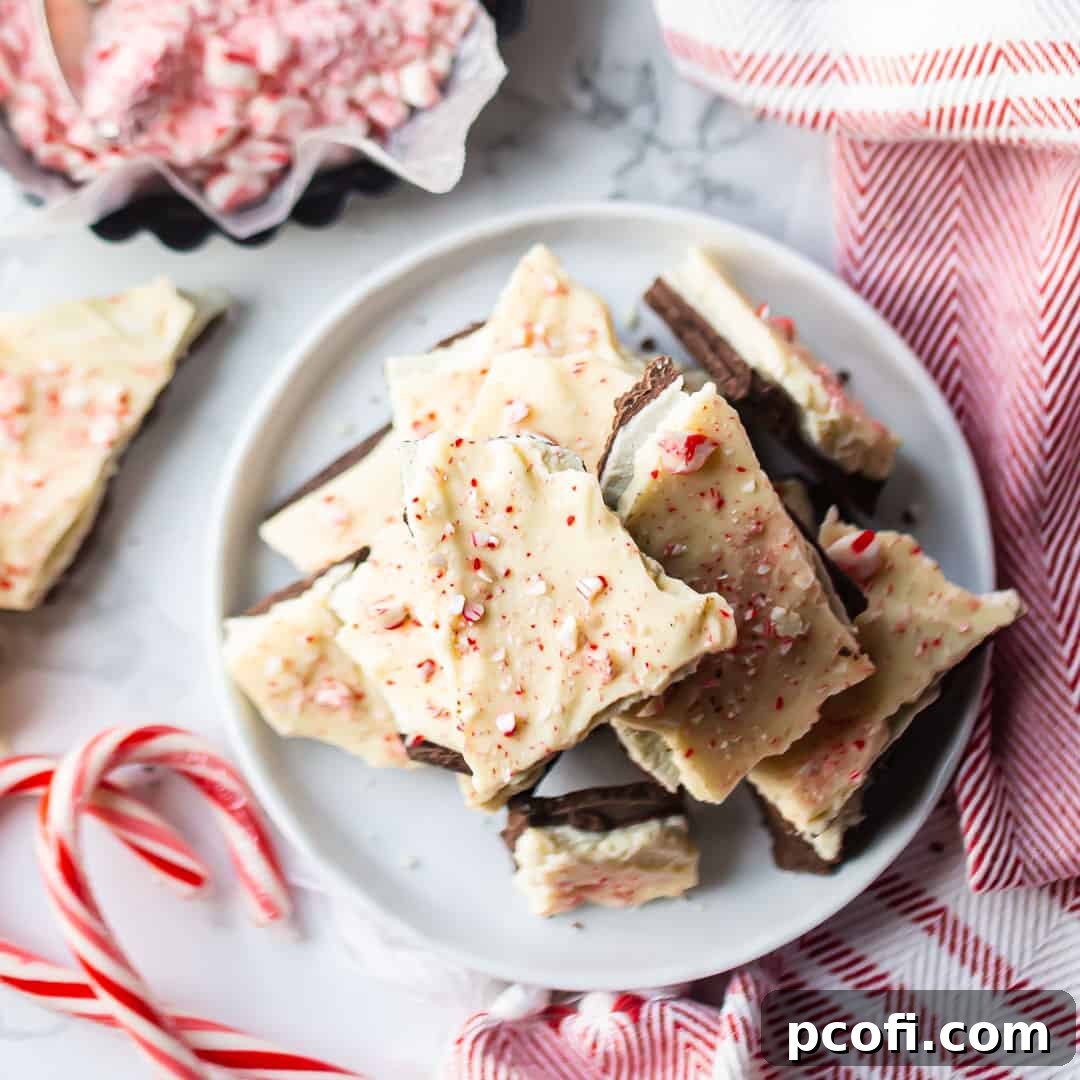 Overhead image of a stack of festive chocolate peppermint bark with candy canes in the background, hinting at the holiday spirit.