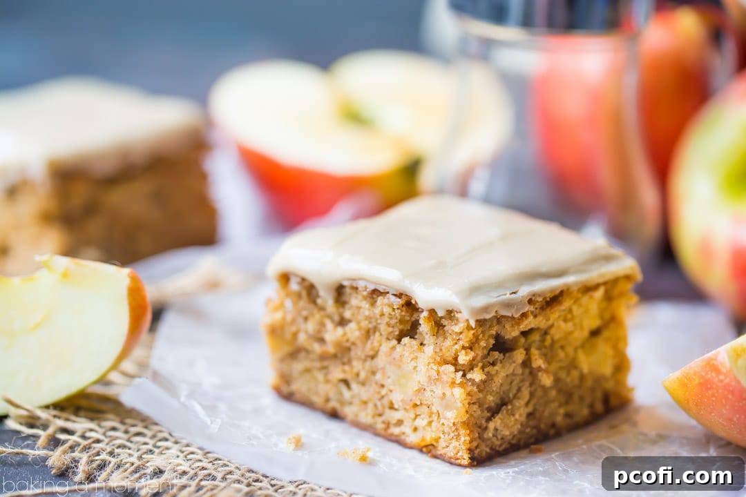 Maple Iced Apple Blondie resting on a napkin with fresh apples visible in the background, highlighting its wholesome ingredients.