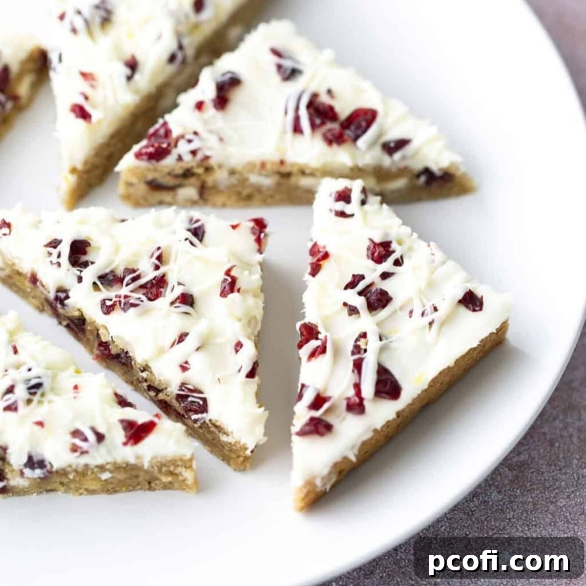 Cranberry bliss bars expertly cut into festive triangles and arranged on a serving plate, highlighting their white frosting and cranberry specks.