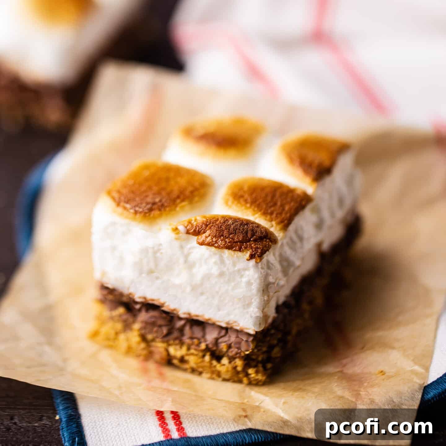 A delicious S'mores bar resting on a piece of parchment paper, with a striped napkin adding a rustic touch, ready to be devoured.