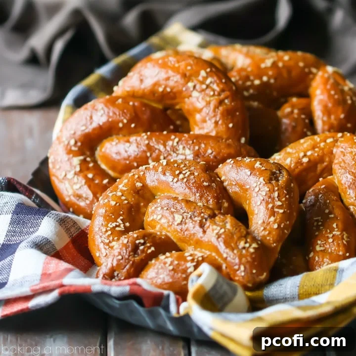 An abundant, inviting basket filled to the brim with perfectly burnished brown, warm soft pretzels, lovingly nestled into an orange plaid napkin, creating a cozy and mouthwatering scene.