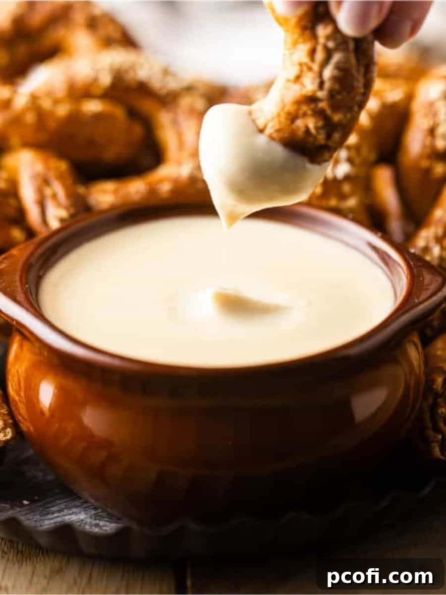 A large, perfectly baked soft pretzel artfully dipped into a rustic crock of golden, bubbling beer cheese, highlighting its creamy, rich texture and inviting warmth.