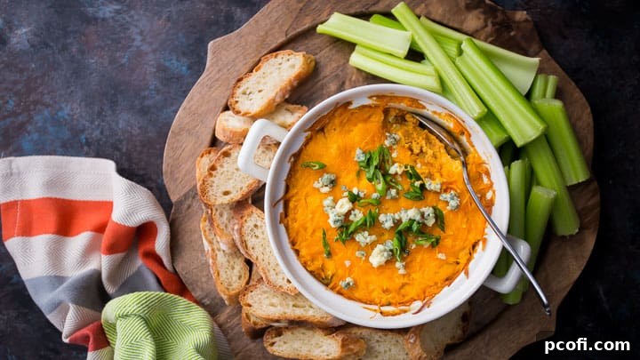 A bubbling hot crock of rich Buffalo Chicken Dip, elegantly garnished with crumbled blue cheese and finely chopped green onions, poised and ready to be served to eager guests.