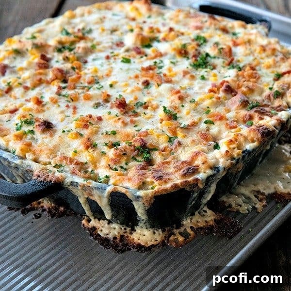 A hot, irresistibly bubbly corn dip, richly laden with tender chicken, savory bacon, and melted cheese, beautifully garnished with fresh green onions for an inviting presentation.