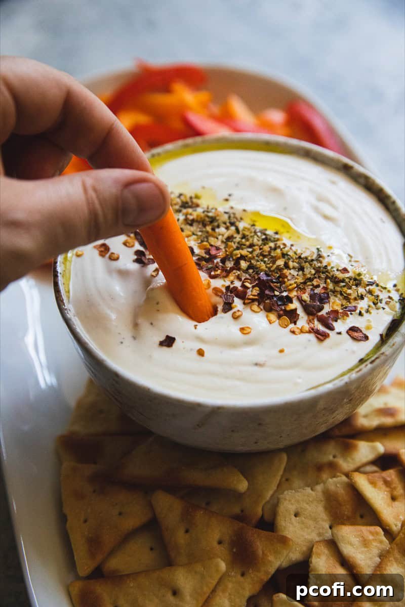 An elegantly prepared smoked whipped feta dip, accompanied by slices of warm pita bread and an assortment of crisp, fresh vegetables, arranged beautifully for a sophisticated dipping experience.