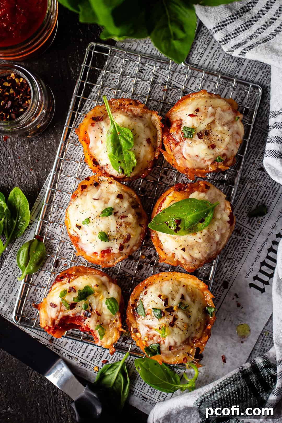 A tempting array of golden-brown pizza puffs, delicately sprinkled with crushed red pepper flakes, meticulously arranged on a wire rack to highlight their appealing texture.