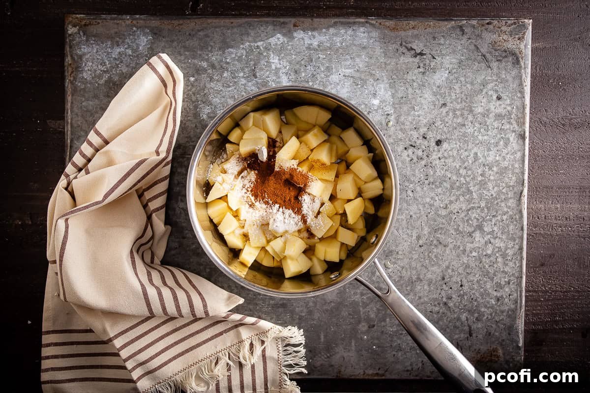 Uncooked apple pie bar filling mixture ready in a saucepan, showing chopped apples and spices before being mixed and heated.