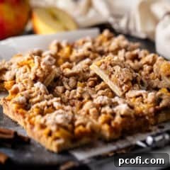 A close-up shot of a single Apple Pie Bar, dusted with powdered sugar, invitingly placed on a surface.