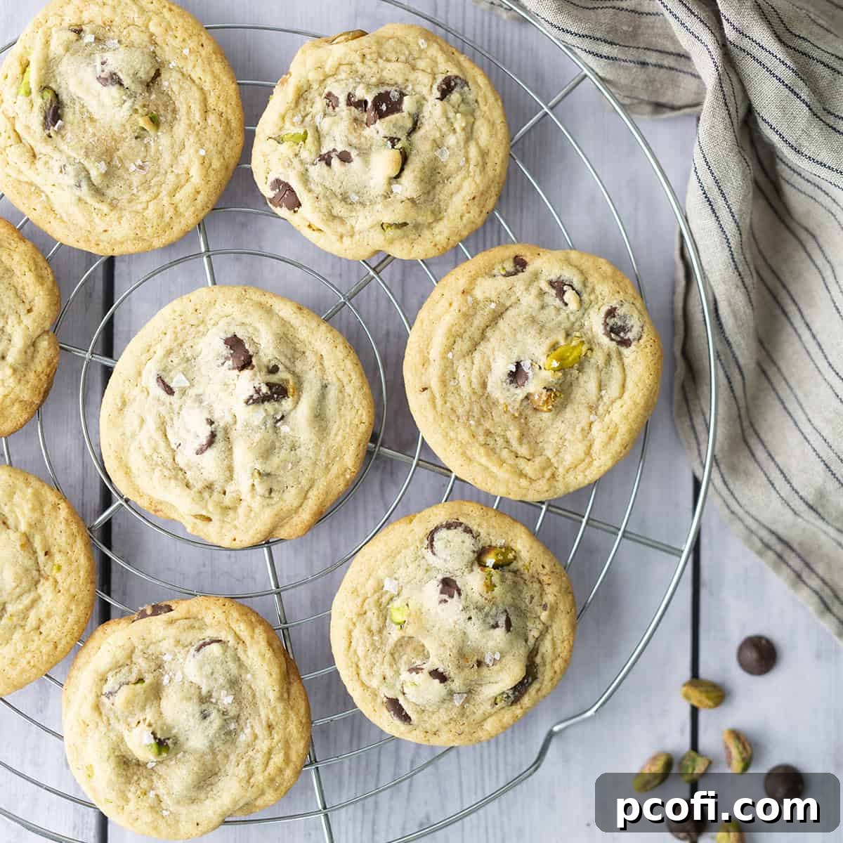 Freshly baked pistachio chocolate chip cookies cooling on a wire rack.