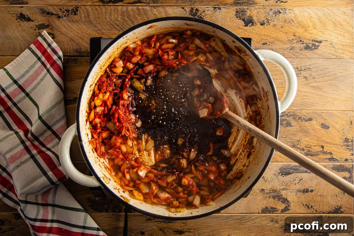 Braciole sauce mixture simmering in a Dutch oven after deglazing with balsamic vinegar.
