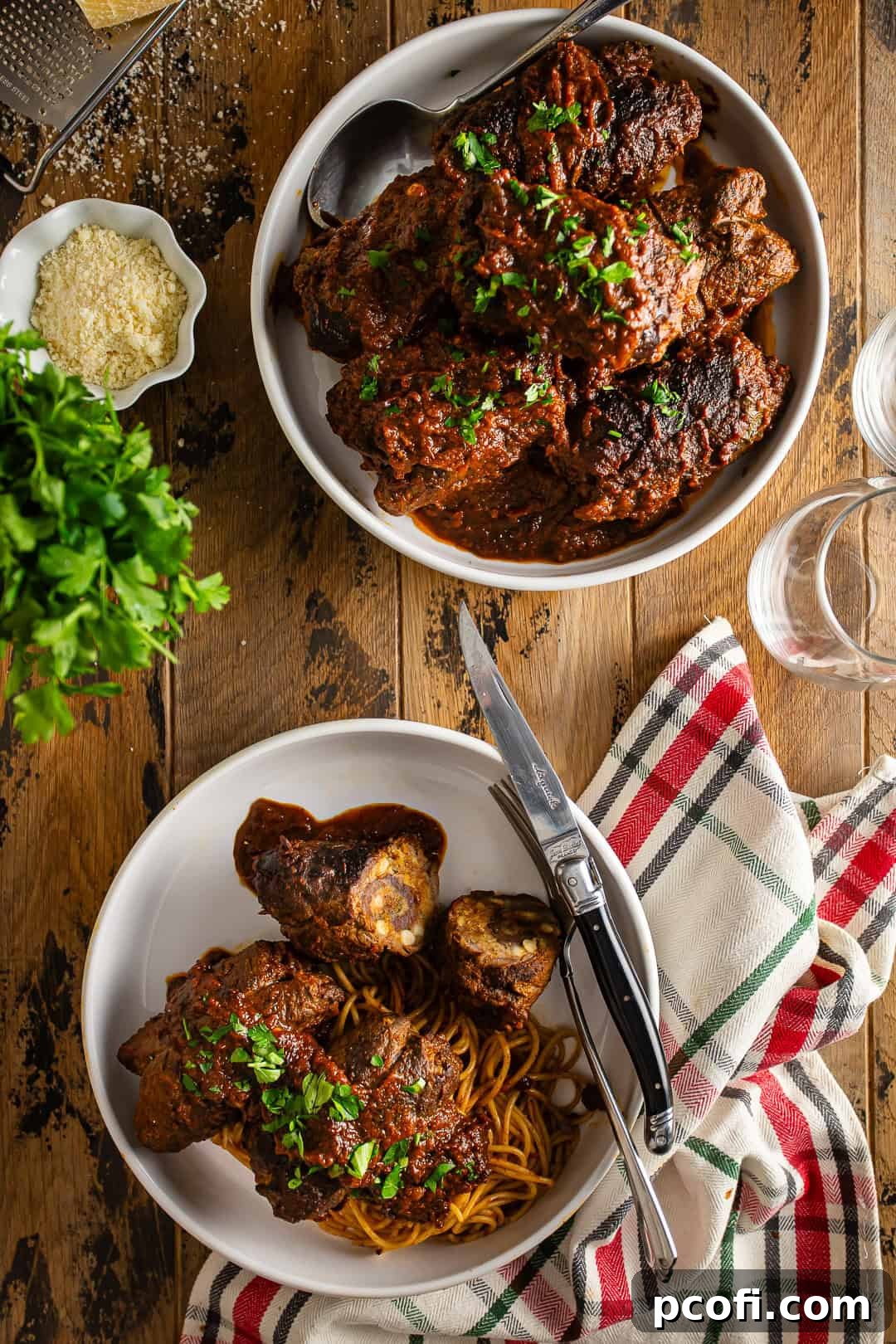 Cooked Braciole served in a large white dish, garnished with parsley and a side of grated Parmesan cheese.