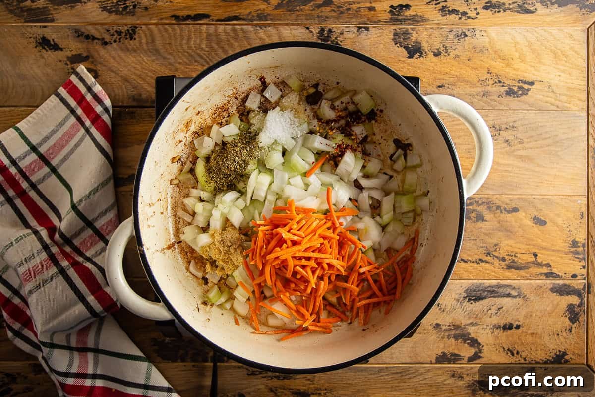 Chopped onions, grated carrots, and seasonings sautéing in a large Dutch oven for Braciole sauce base.
