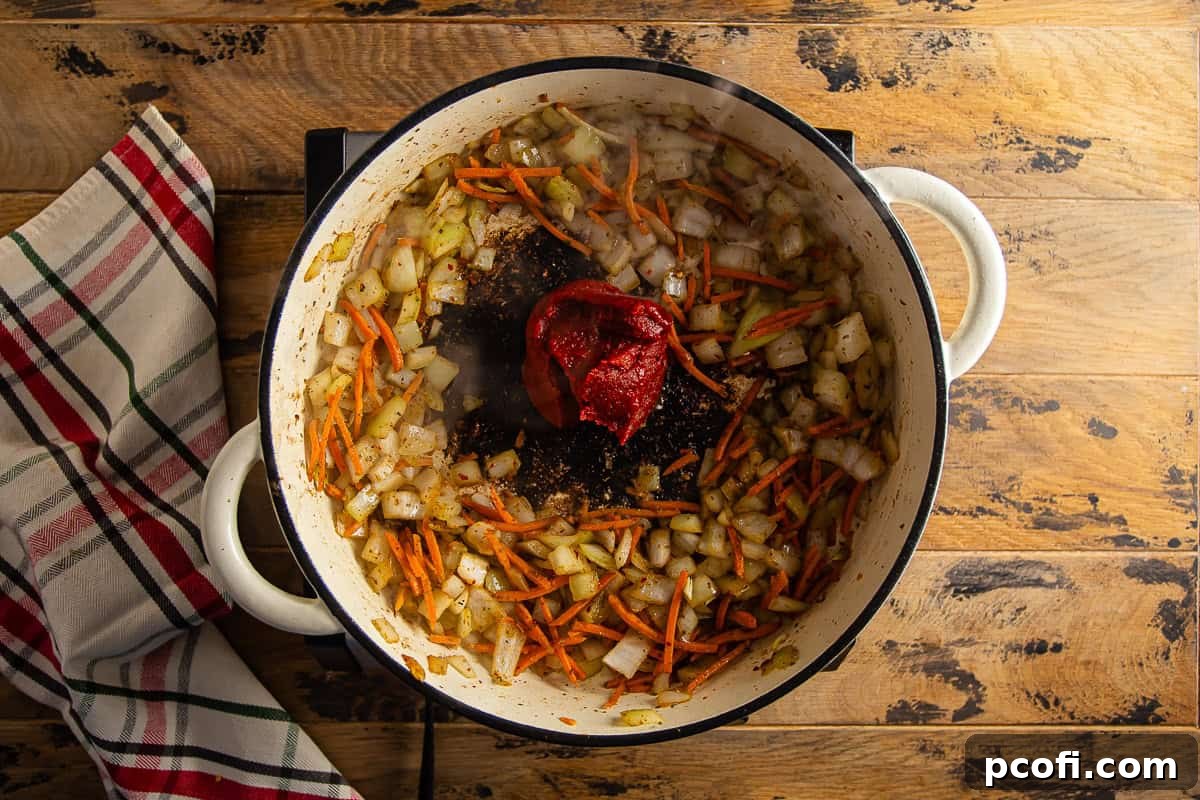 Tomato paste cooking in the center of a Dutch oven with sautéed vegetables and balsamic vinegar.