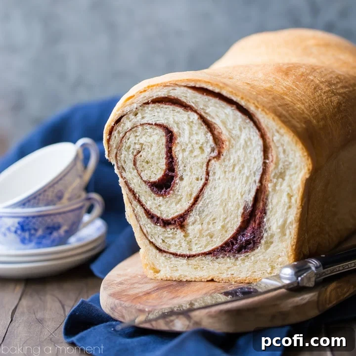 A warm, freshly baked Homemade Cinnamon Bread loaf, sliced to reveal a beautiful ribbon of cinnamon sugar swirling throughout, ready to be toasted and buttered.
