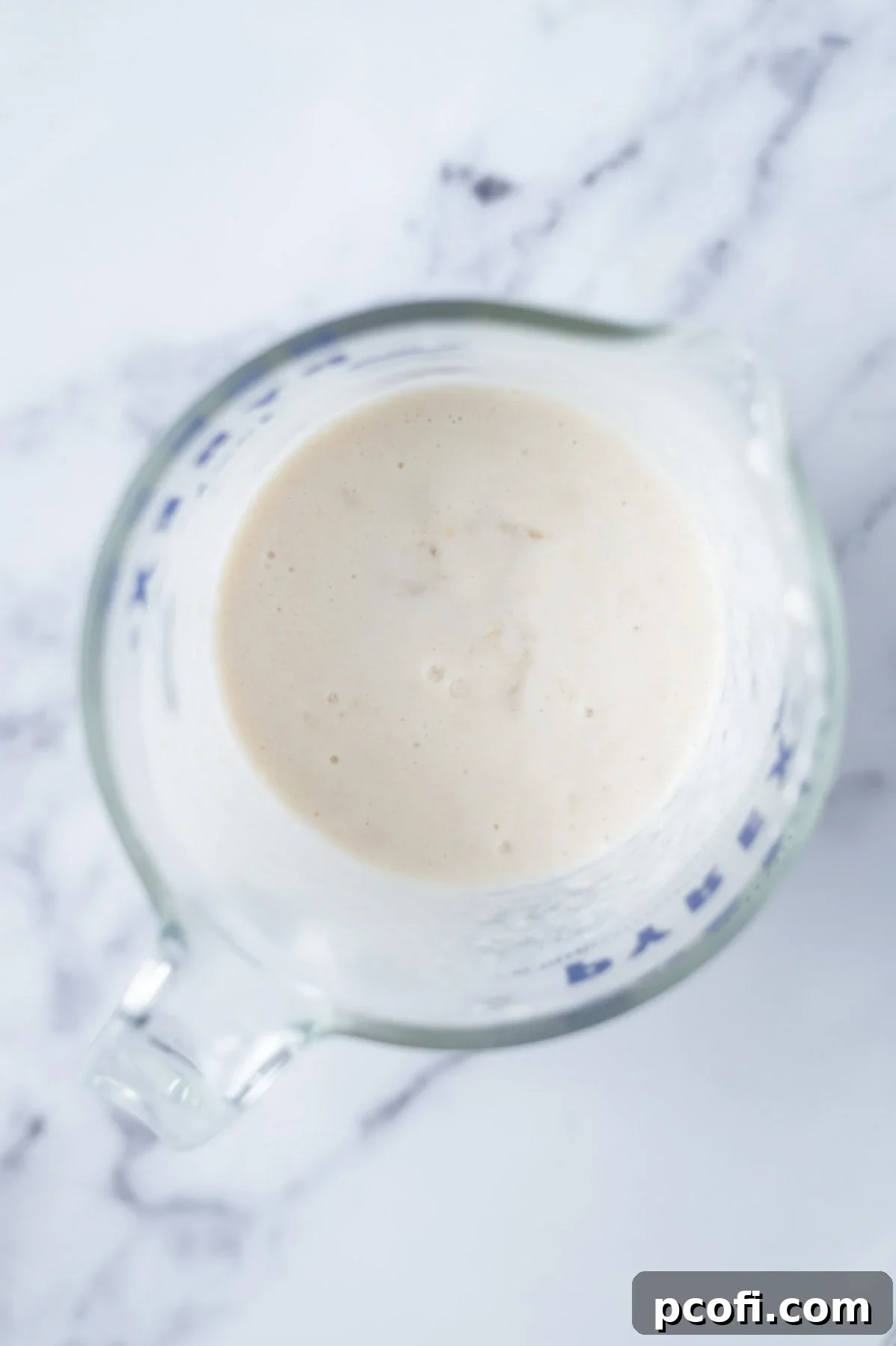 Heavy cream, mashed ripe bananas, and vanilla extract are mixed in a spouted measuring cup, forming the wet ingredients for banana scones.