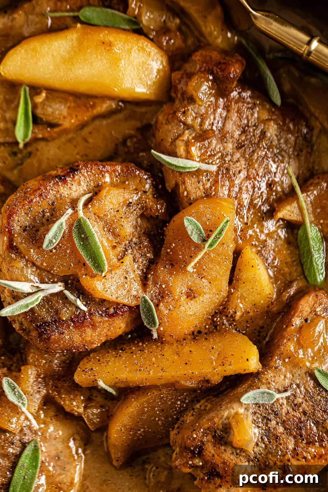 Pork Chops with Apples in a skillet and fresh sage on top, ready to serve.