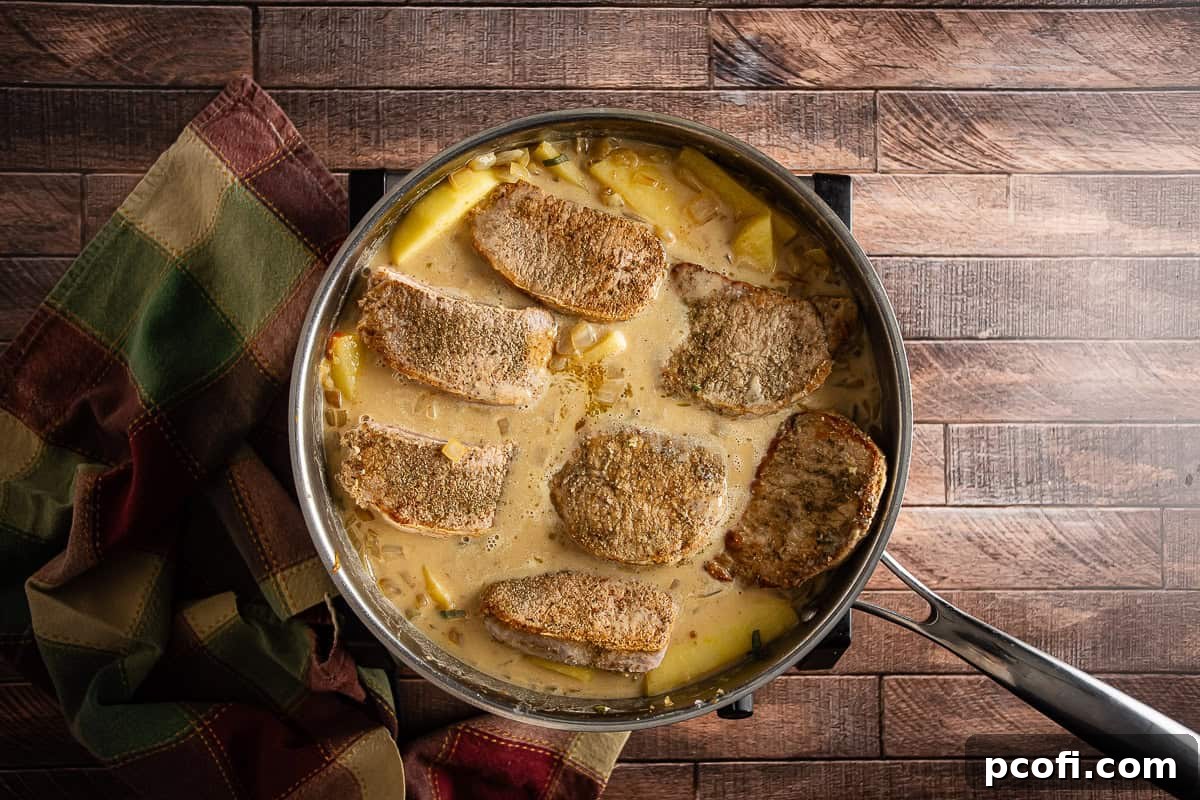 Pork chops and apples simmering in the pan.