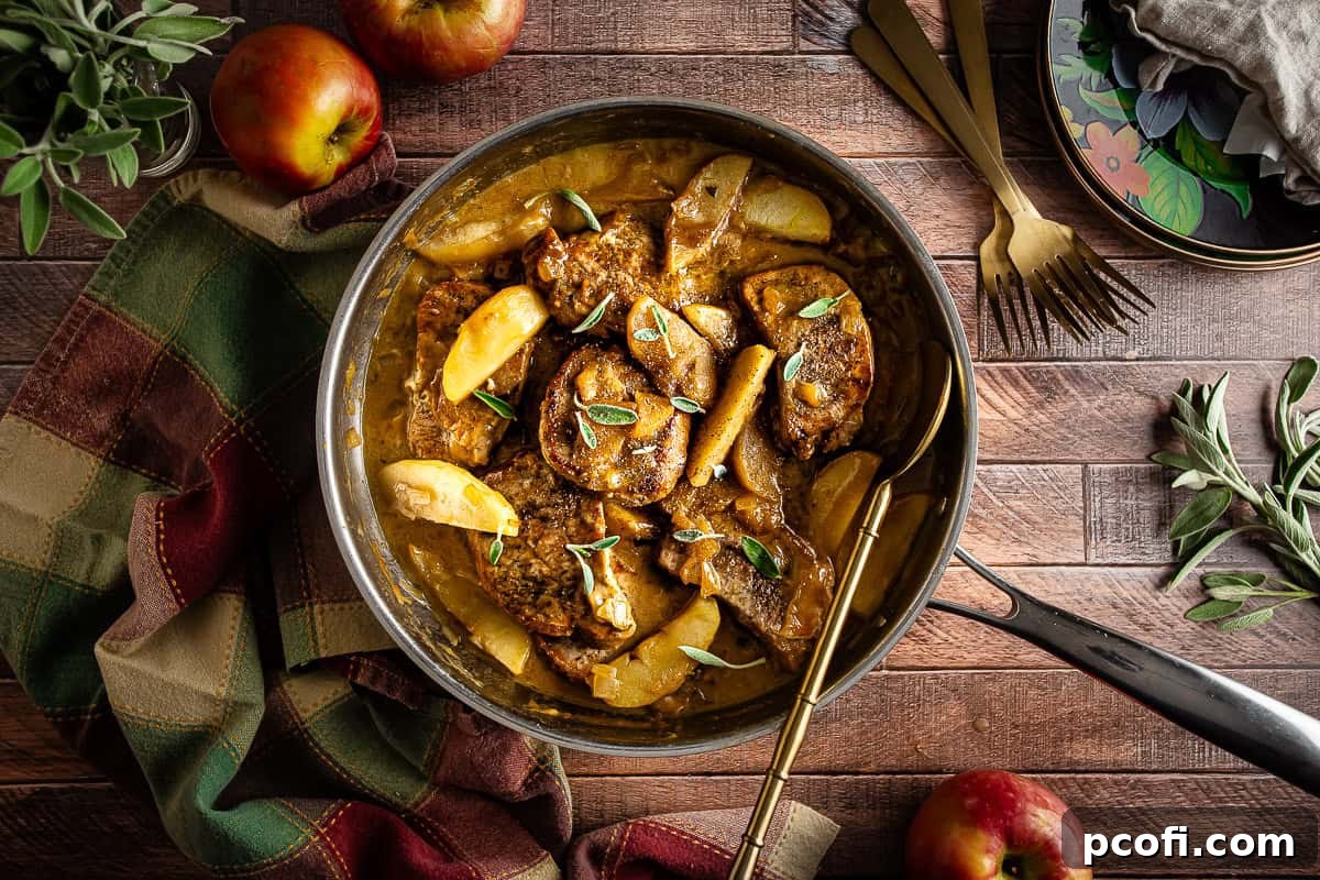 Pork chops and apples after being garnished with sage in a large skillet.