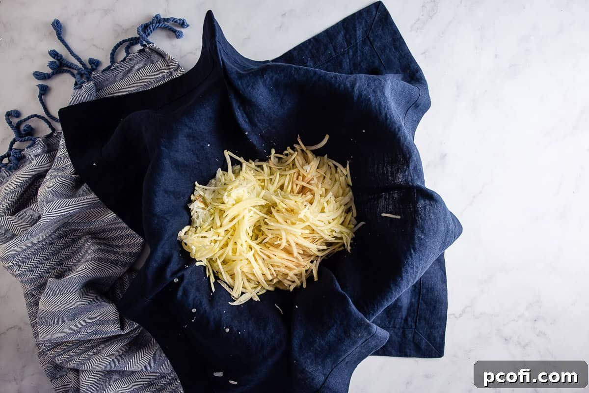 Shredded potatoes and onions for potato pancakes being drained of all the water in a kitchen towel.