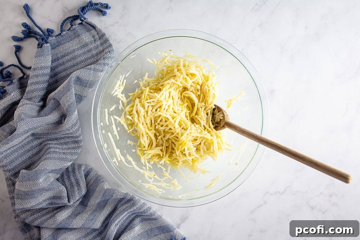 A bowl of potato pancake mixture with flour, egg, salt, and pepper, next to a skillet heating oil.