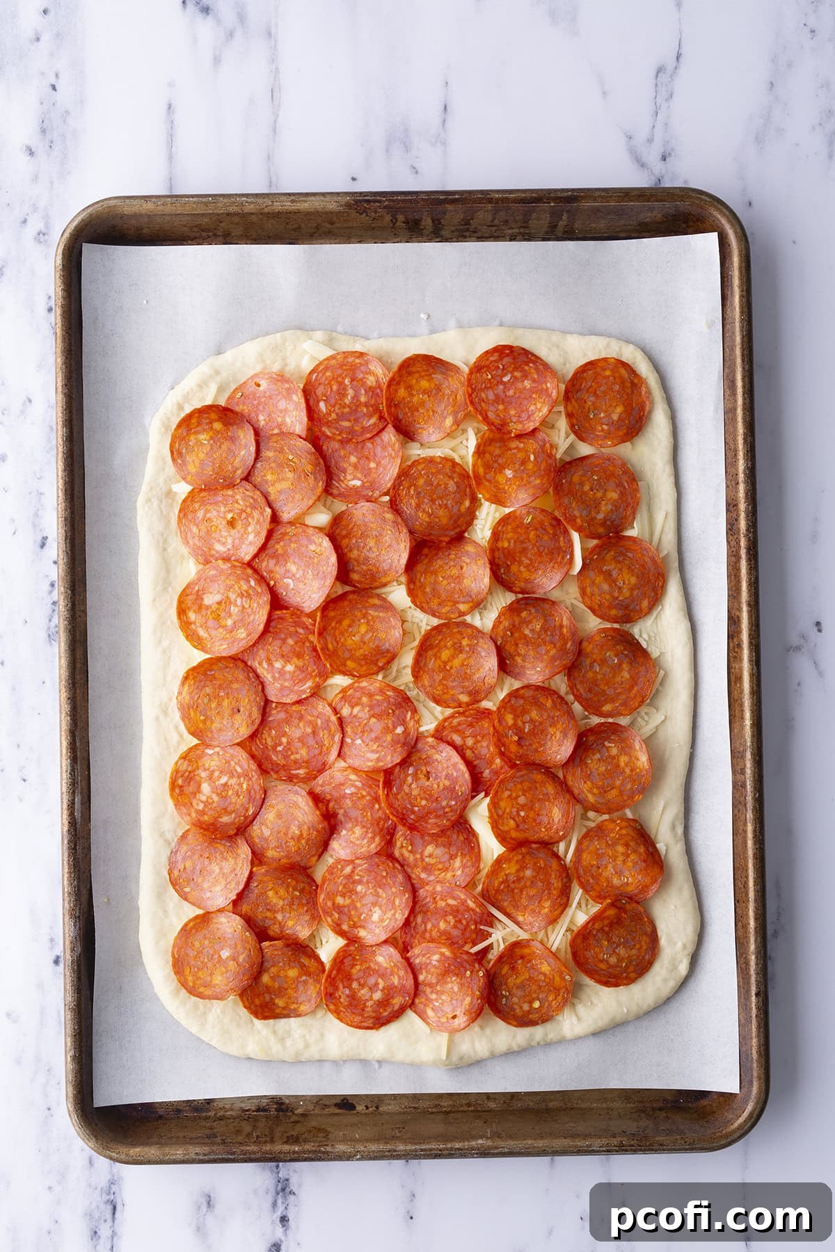 Pepperoni slices arranged over cheese on dough