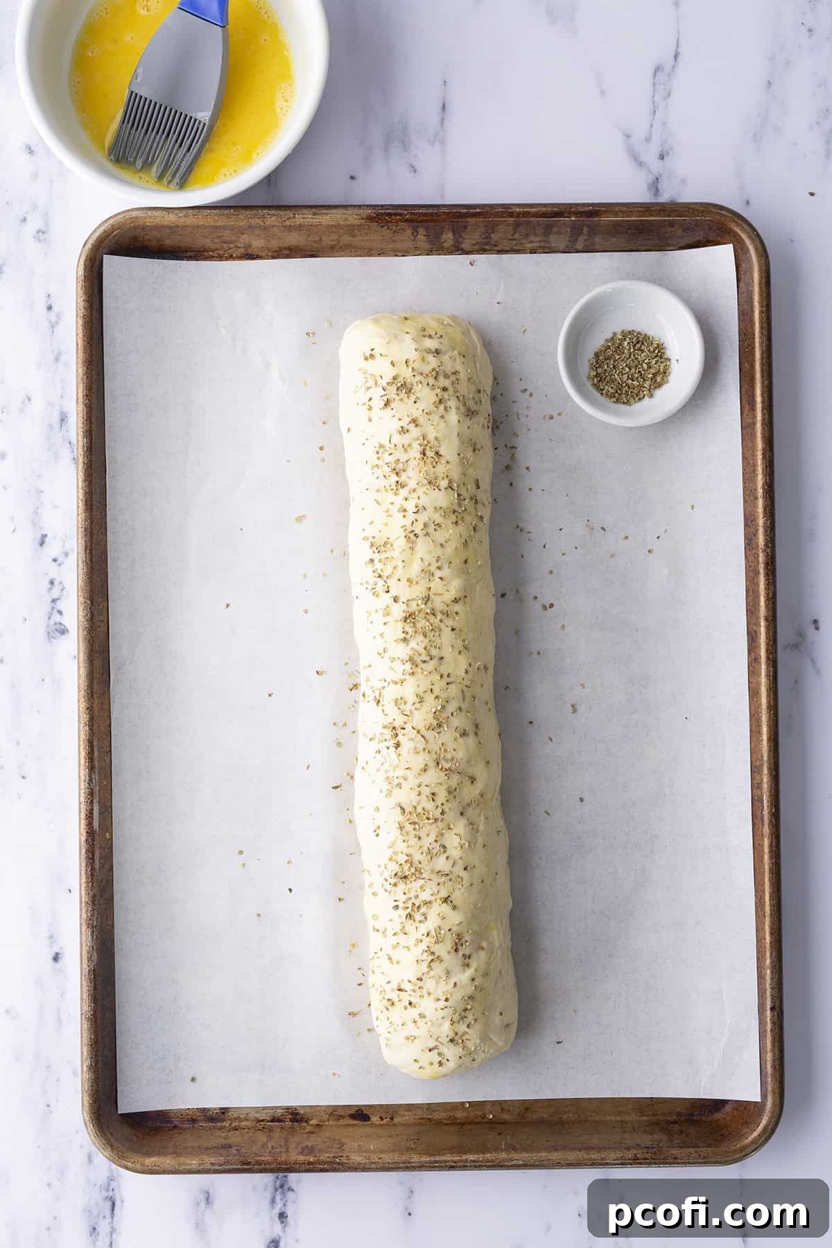 Oregano sprinkled on top of unbaked pepperoni bread