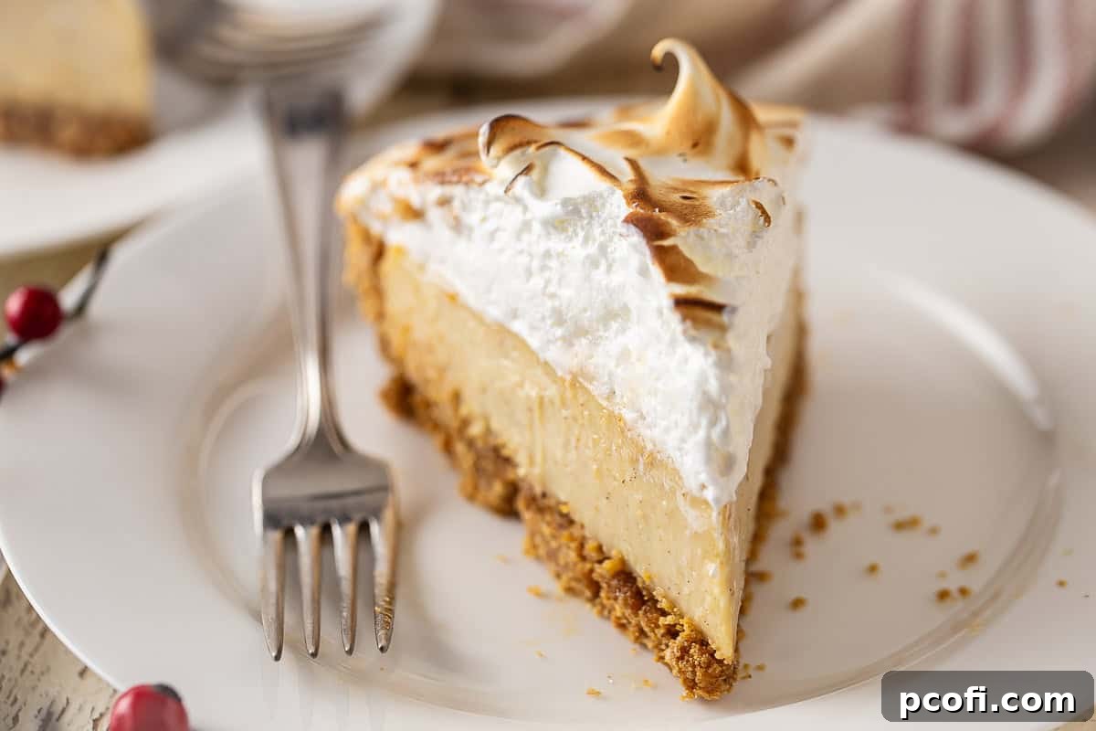 A perfectly sliced piece of eggnog pie, showcasing the creamy filling and toasted meringue, served on a white plate with a fork.
