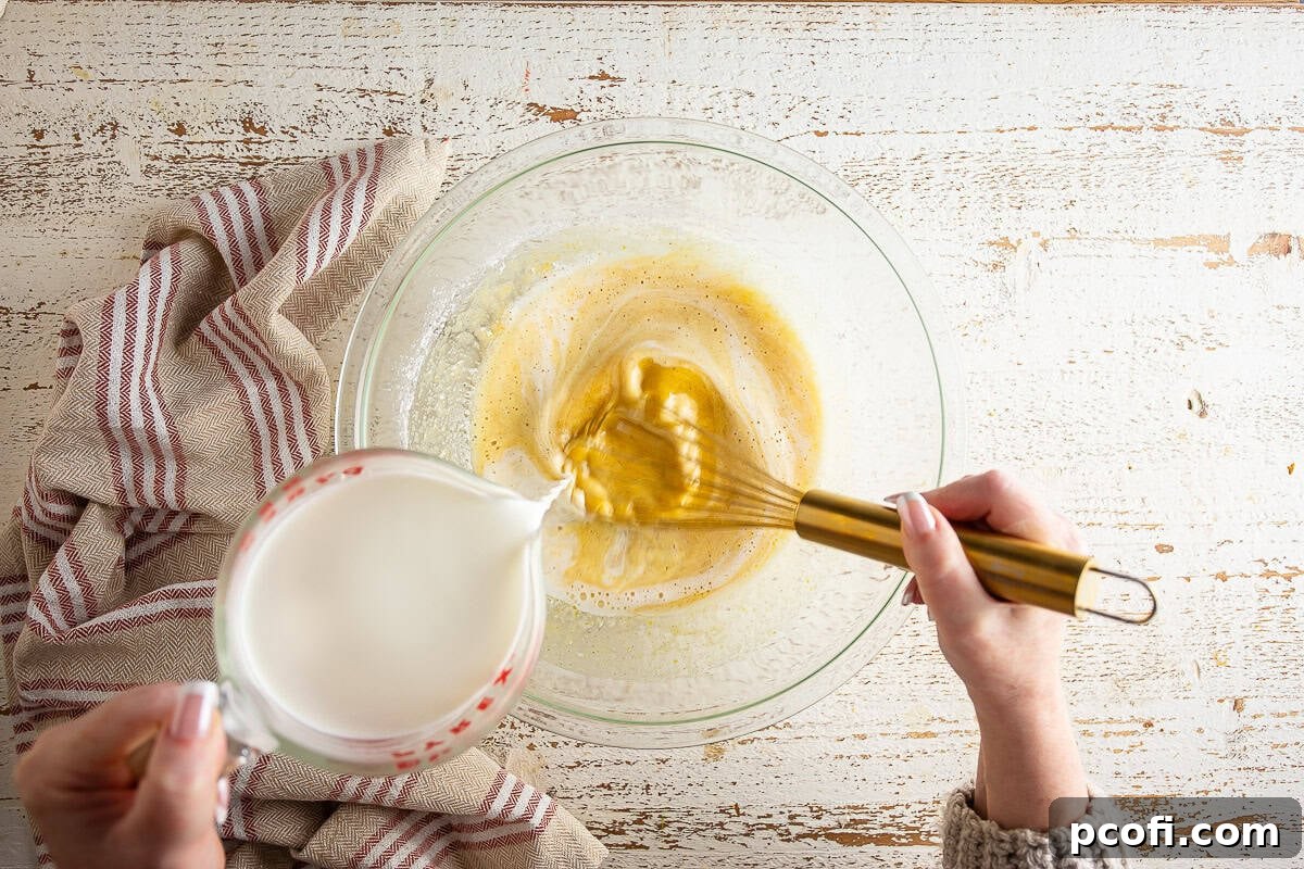 Hot half-and-half being slowly whisked into the egg and sugar mixture for the eggnog pie filling.