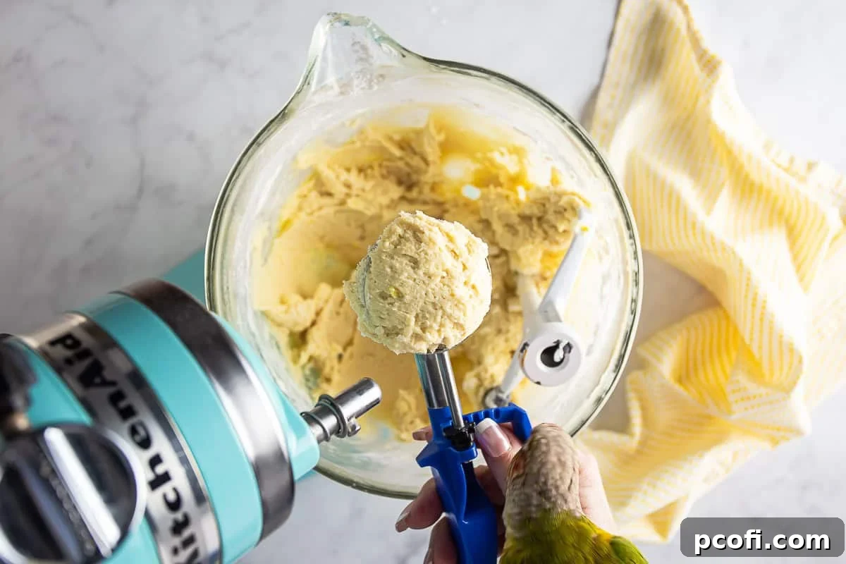 Cookie dough for ricotta cookies being portioned into individual cookies with a cookie scoop.