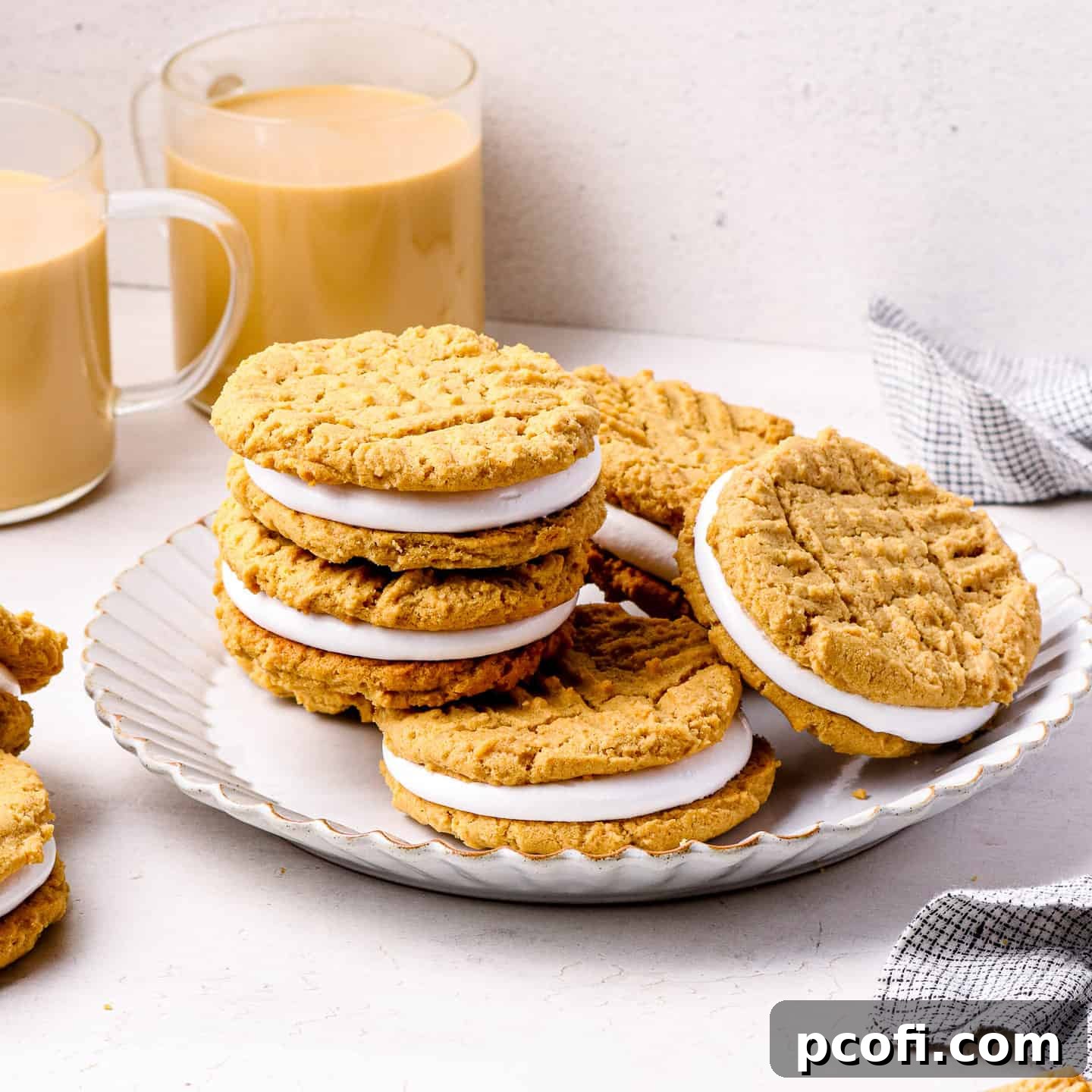 Delicious Fluffernutter Cookies stacked on a white plate, with cups of coffee in the background.