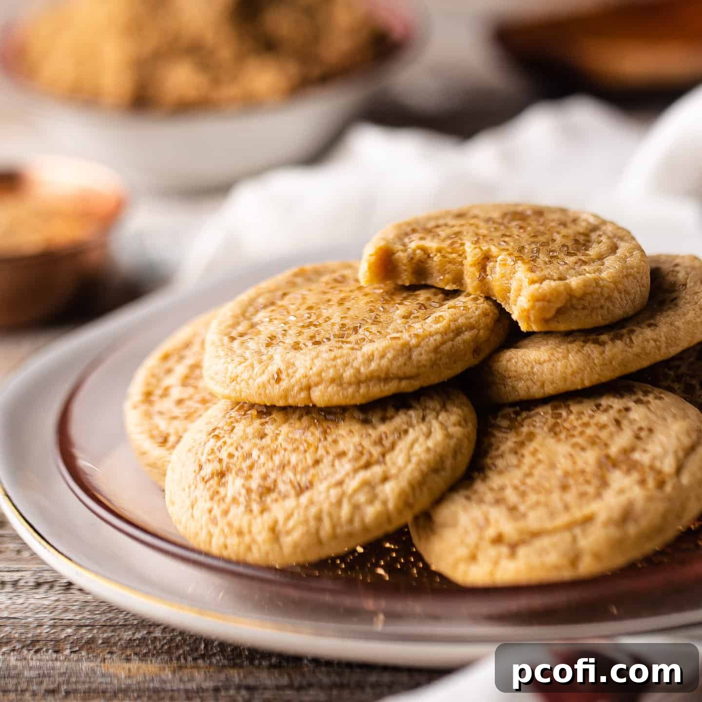 A high pile of golden brown sugar cookies on a charming pink glass plate.