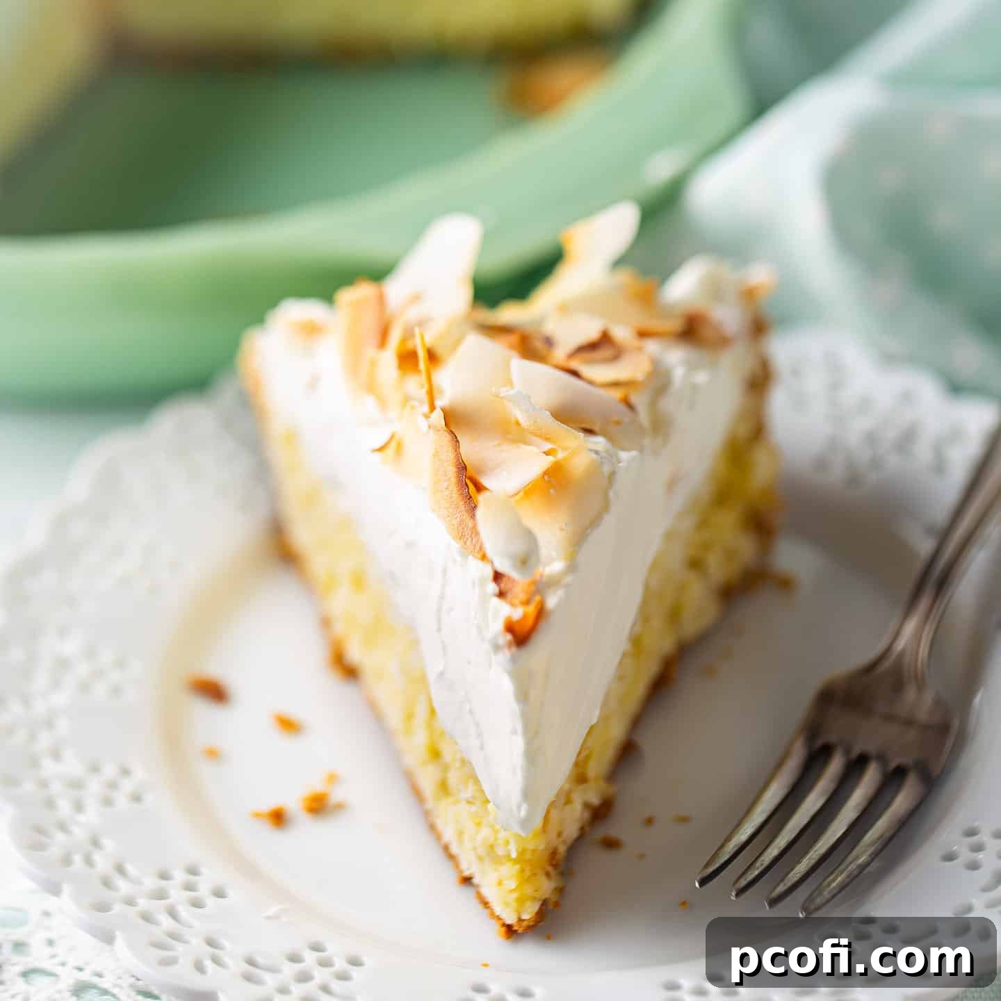 A slice of coconut cream pie on a lacy porcelain plate.