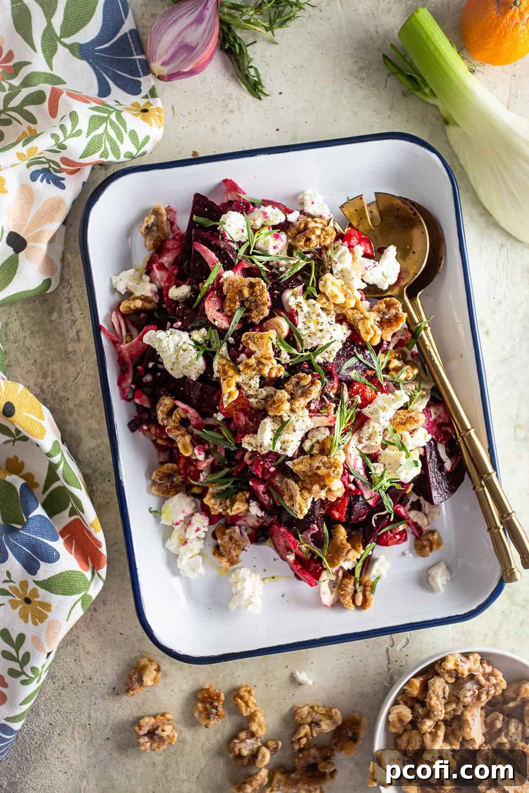 Beet salad with gold serving spoons, beautifully arranged on a white platter.