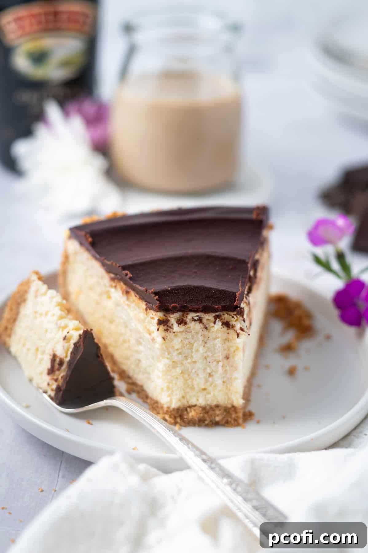 Slice of Baileys cheesecake on a plate with a bite on a fork, ready to be enjoyed.